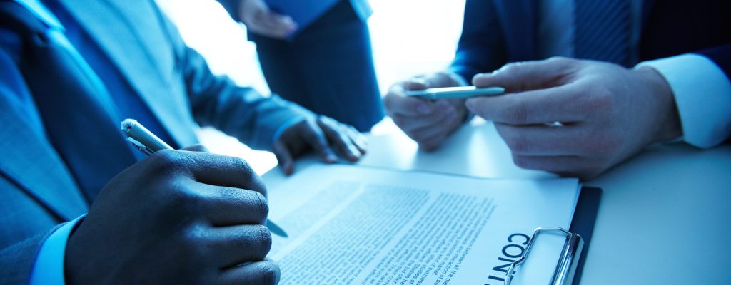 Image of contract on workplace and group of partners making decision to sign it